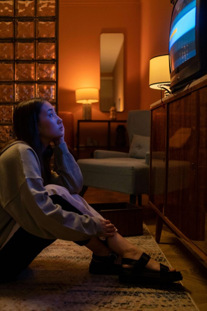 Asian woman sitting on the floor while watching TV at home.